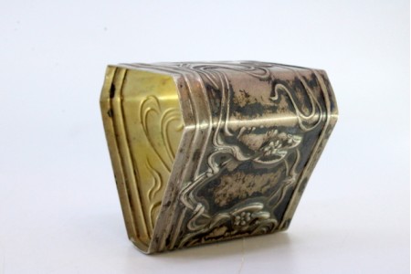 Argola de guardanapo em prata de forma triangular com laços e flores envolvendo cartela para monograma.